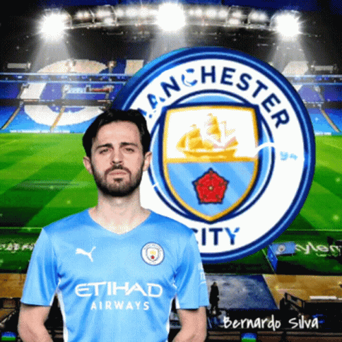 A Man In A Blue Etihad Airways Jersey Stands In Front Of Manchester City 'S Logo GIF
