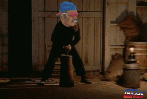 A Man In A Blue Hat Is Holding A Barrel In Front Of A Sign That Says ' Kill ' GIF