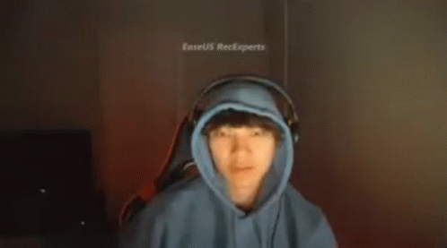 a man in a blue hoodie and headphones is making a funny face .