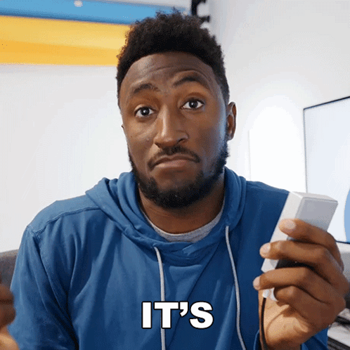 A Man In A Blue Hoodie Holds A Remote Control And Says It 'S In White Letters GIF