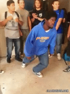 A Man In A Blue Hoodie Is Dancing In Front Of A Group Of People .. GIF