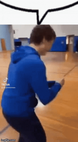 a man in a blue hoodie is dancing on a wooden floor .