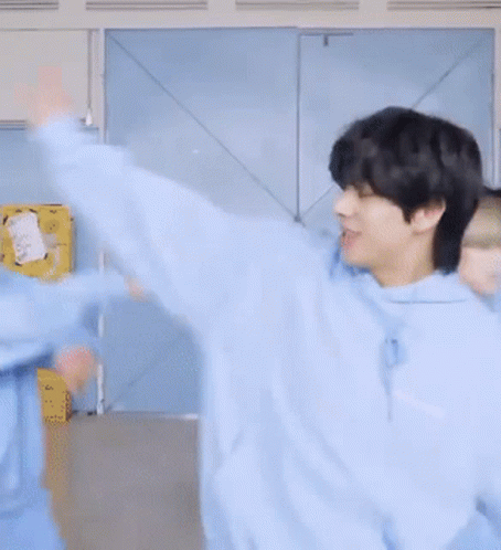 A Man In A Blue Hoodie Is Smiling And Looking At The Camera GIF