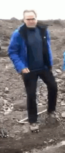 A Man In A Blue Jacket And Black Pants Is Dancing In The Dirt . GIF