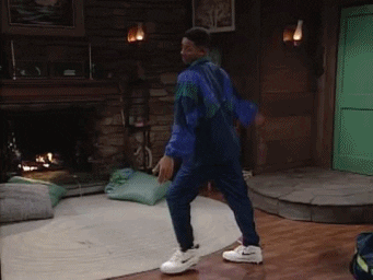A Man In A Blue Jacket And White Nike Shoes Is Dancing In A Living Room GIF