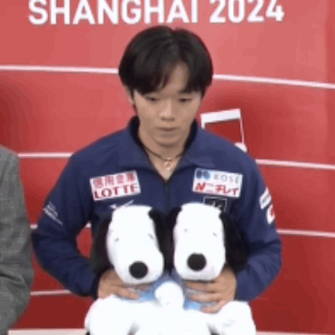 A Man In A Blue Jacket Holding Two Stuffed Snoopy Dogs GIF