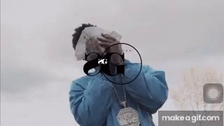 A Man In A Blue Jacket Is Covering His Face With Money And A Gun . GIF