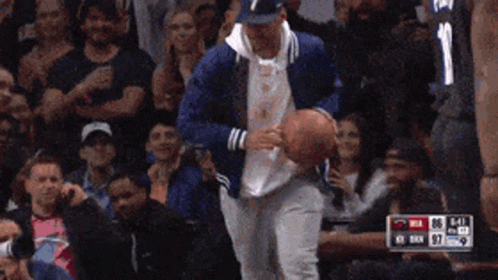 A Man In A Blue Jacket Is Holding A Basketball In Front Of A Crowd With The Number 11 On His Jersey GIF