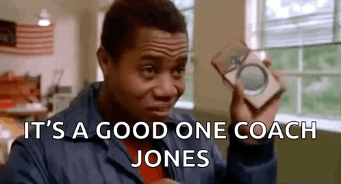 A Man In A Blue Jacket Is Holding A Piece Of Paper That Says It 'S A Good One Coach Jones GIF