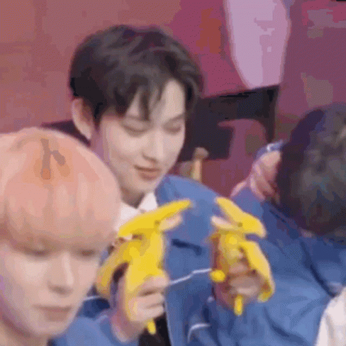 A Man In A Blue Jacket Is Holding A Stuffed Banana In His Hands . GIF