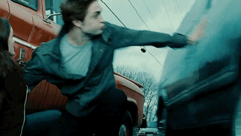 A Man In A Blue Jacket Is Reaching For A Car GIF