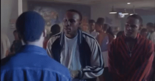 A Man In A Blue Jacket Is Standing In A Crowd GIF