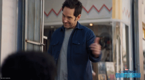 Man In Blue Jacket In Front Of Quantumania Building GIF