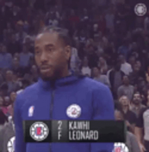A Man In A Blue Jacket Is Standing In Front Of A Crowd In A Basketball Game . GIF