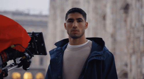 a man in a blue jacket is standing in front of a red camera