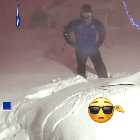 A Man In A Blue Jacket Is Standing In The Snow Next To A Smiley Face With Sunglasses On GIF