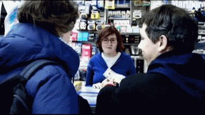 A Man In A Blue Jacket Is Talking To A Woman In A Store That Says Marlboro On The Wall GIF
