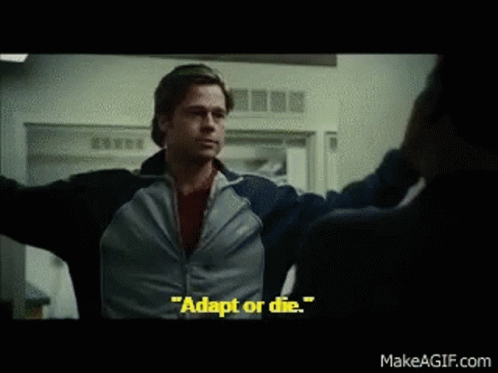A Man In A Blue Jacket Says " Adapt Or Die " In A Movie Scene GIF