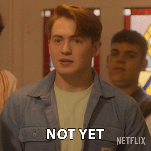 A Man In A Blue Jacket Says Not Yet In Front Of A Stained Glass Window GIF