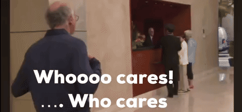 A Man In A Blue Jacket Stands In Front Of A Sign That Says Who Cares Who Cares GIF
