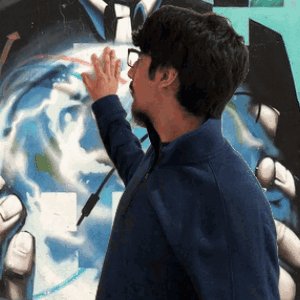 A Man In A Blue Jacket Touches A Painting Of A Man In A Suit And Tie GIF