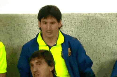 a man in a blue jacket with a yellow collar is standing next to another man in a yellow shirt