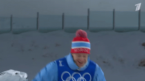 A Man In A Blue Jacket With The Word Biathlon On His Chest GIF