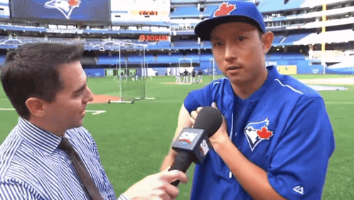 A Man In A Blue Jays Uniform Is Being Interviewed By A Reporter GIF