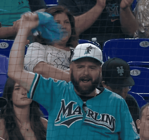 A Man In A Blue Marlins Jersey Is Cheering GIF