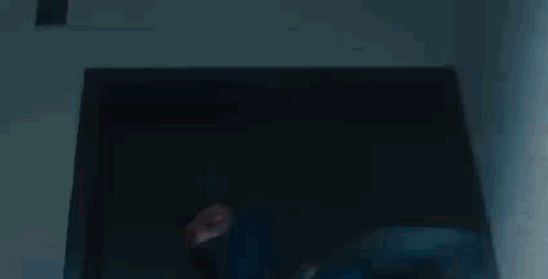 A Man In A Blue Mask Is Standing In Front Of A Glass Door . GIF