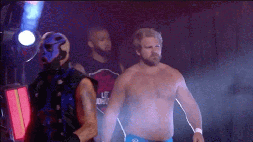 A Man In A Blue Mask Is Standing Next To A Man In A Red Shirt With The Word Life On It . GIF