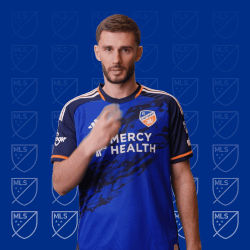 A Man In A Blue Mercy Health Jersey Holds His Finger To His Lips GIF