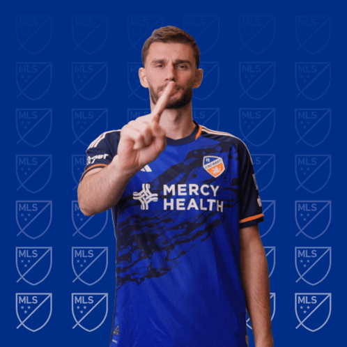 A Man In A Blue Mercy Health Jersey Holds Up A Finger GIF