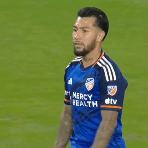 a man in a blue mercy health jersey stands on a field