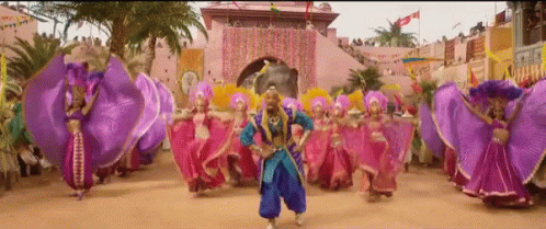 A Man In A Blue Outfit Is Dancing In Front Of A Crowd Of People GIF