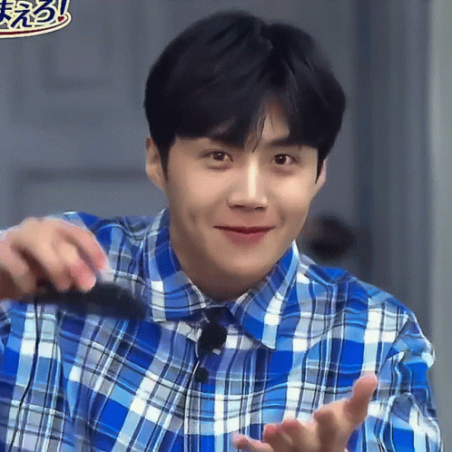 A Man In A Blue Plaid Shirt Is Smiling And Holding Something GIF