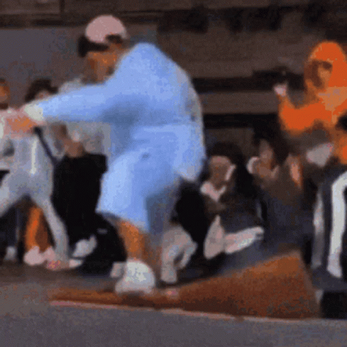 A Man In A Blue Robe Is Standing In Front Of A Crowd Of People . GIF