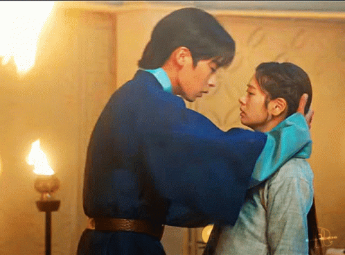 a man in a blue robe is touching a woman 's forehead .