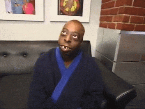 A Man In A Blue Robe Sits On A Couch GIF