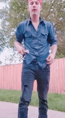 A Man In A Blue Shirt And Black Jeans Is Dancing GIF