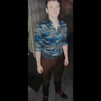 A Man In A Blue Shirt And Blue Shoes Is Standing In A Room GIF