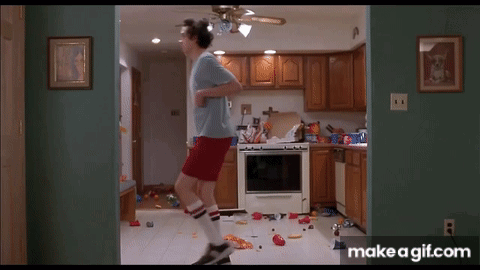 A Man In A Blue Shirt And Red Shorts Is Jumping In A Kitchen . GIF