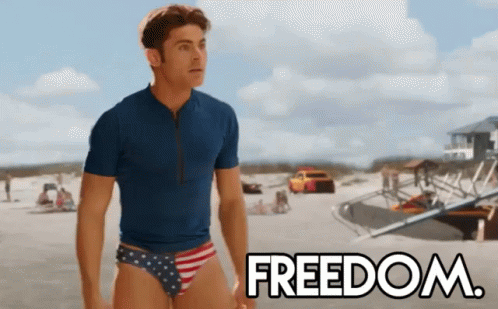 A Man In A Blue Shirt And Red White And Blue Swim Trunks Is Standing On A Beach With The Word Freedom In The Background GIF