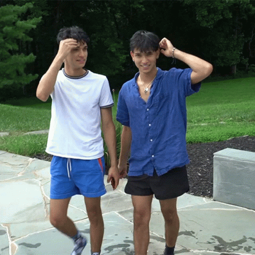 A Man In A Blue Shirt And Shorts Is Walking With Another Man In A White Shirt GIF