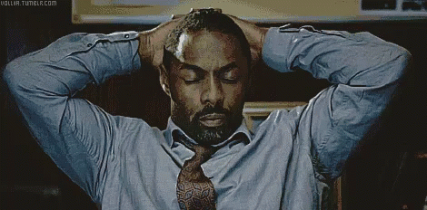 A Man In A Blue Shirt And Tie Holds His Hands To His Head GIF