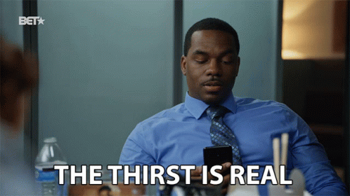 A Man In A Blue Shirt And Tie Is Holding A Cell Phone And Says " The Thirst Is Real " GIF