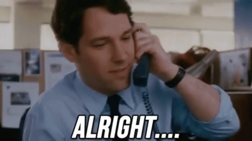 A Man In A Blue Shirt And Tie Is Talking On A Telephone And Saying `` Alright '' . GIF