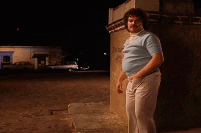 A Man In A Blue Shirt And White Pants Is Leaning Against A Wall GIF