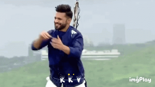 A Man In A Blue Shirt And White Shorts Is Dancing In A Field GIF