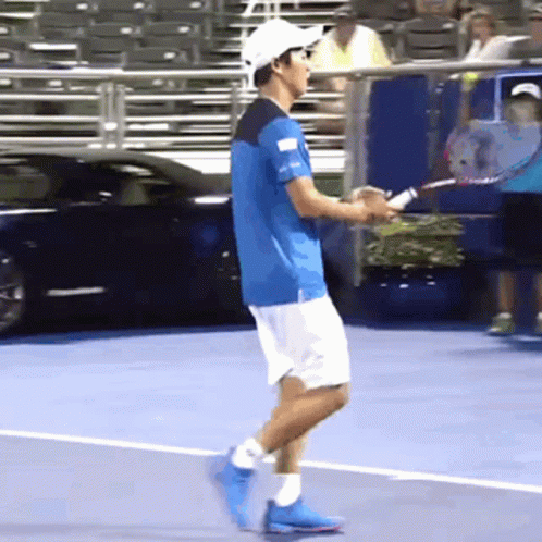 A Man In A Blue Shirt And White Shorts Is Holding A Tennis Racket GIF
